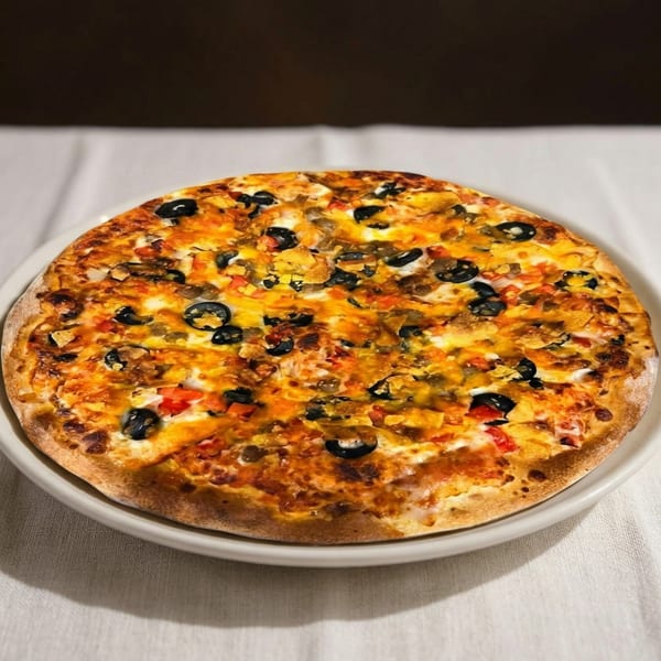 A whole pizza topped with melted cheese, black olives, and diced tomatoes on a white plate.